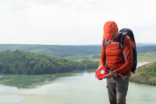 Uomo caucasico viaggiatore che usa un kit di pronto soccorso nelle montagne vicino al lago