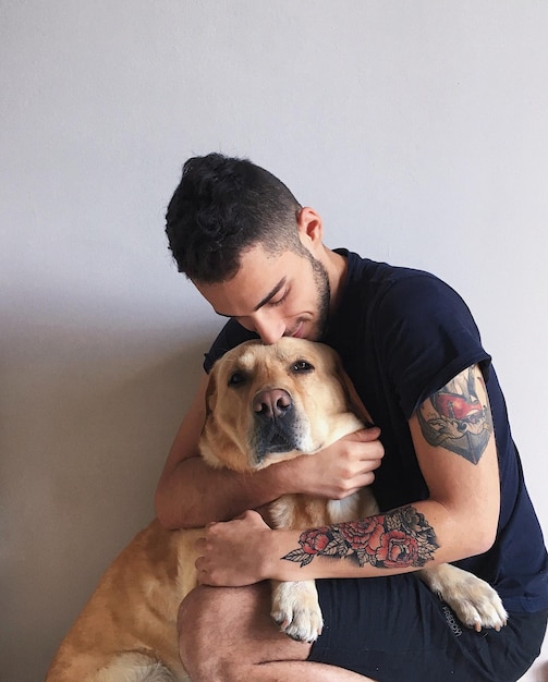 Uomo che abbraccia il cane contro il muro