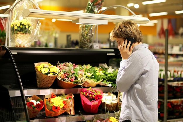 Uomo che acquista fiori in un garden center utilizzando lo smartphone