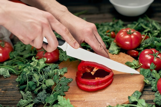 Uomo che affetta la paprika sul tavolo della cucina