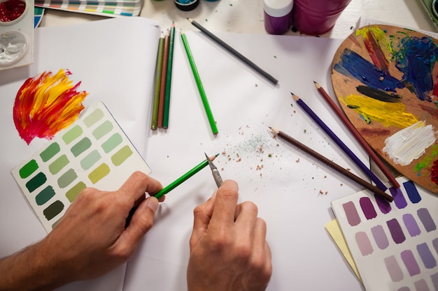 Uomo che affila matita colorata nella classe del disegno