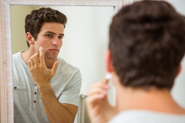 Uomo che applica crema idratante sul suo viso