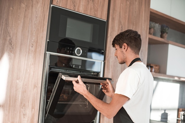 Uomo che apre il forno nella cucina di casa