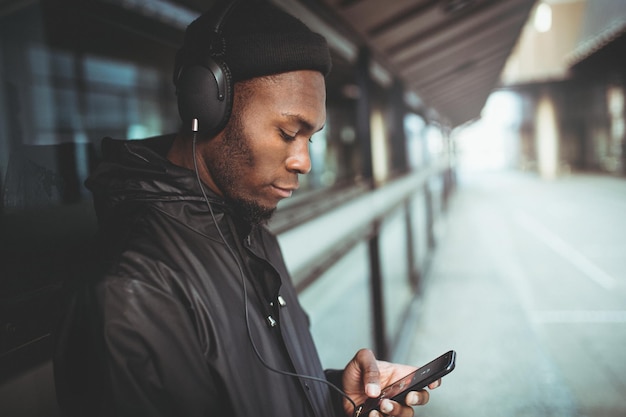 Uomo che ascolta musica con le cuffie mentre si appoggia alla finestra