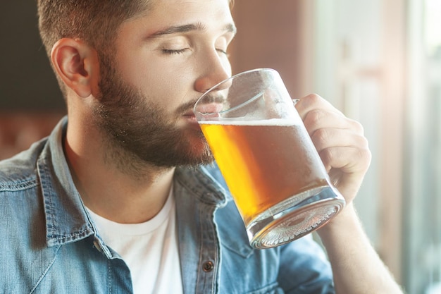 Uomo che assaggia birra con gli occhi chiusi nella caffetteria