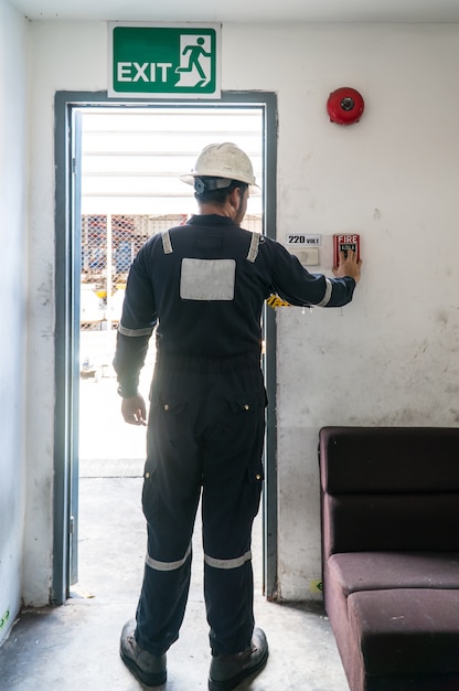 Uomo che attiva l&#39;allarme antincendio durante l&#39;incendio vicino alla porta di uscita di emergenza.