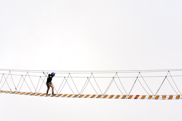 Uomo che attraversa il ponte di corda sull'abisso nelle montagne nebbiose