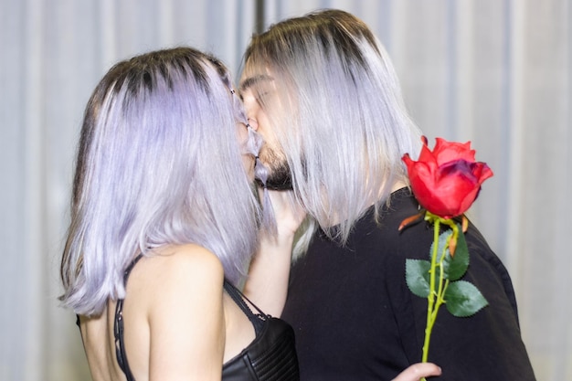 Uomo che bacia la sua ragazza a casa mentre la ragazza tiene in mano una rosa Ragazzo che bacia la sua ragazza mentre lei tiene in mano una rosa