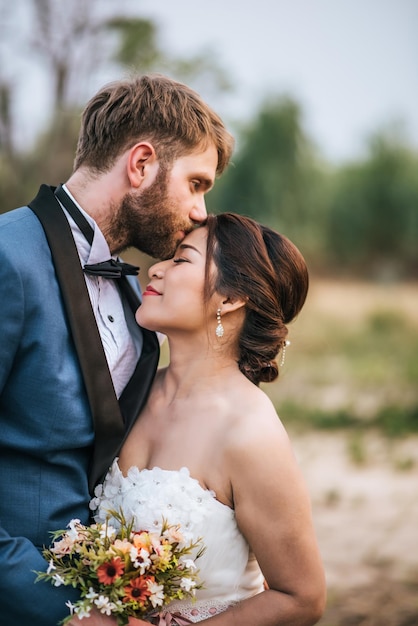 Uomo che bacia una donna sulla fronte contro il cielo