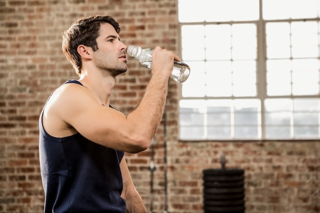 Uomo che beve acqua in palestra