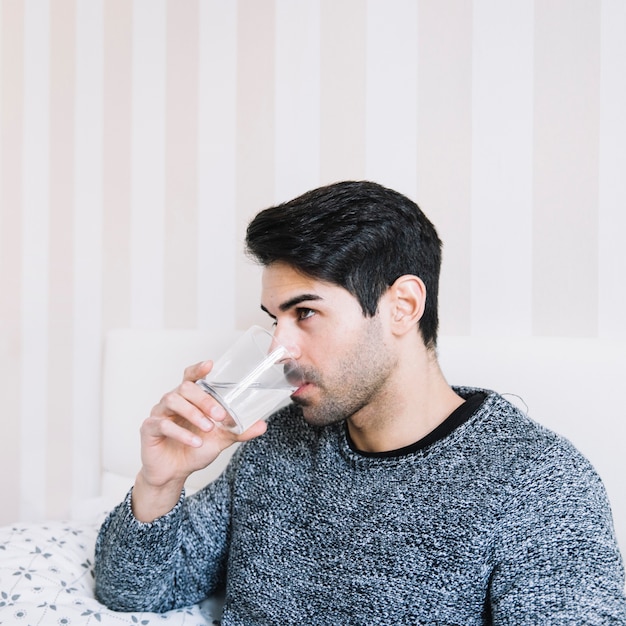 Uomo che beve acqua nella camera da letto