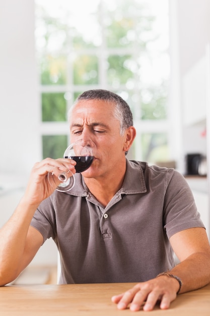 Uomo che beve bicchiere di vino rosso