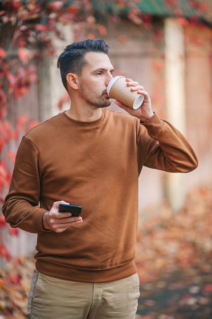 Uomo che beve caffè nel parco d'autunno