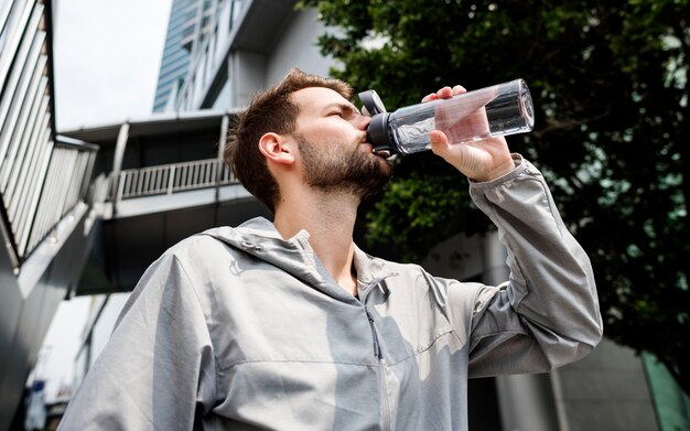 Uomo che beve da una bottiglia d&#39;acqua