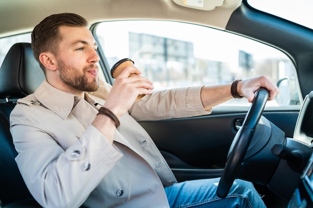 Uomo che beve il caffè del mattino mentre guida l'auto