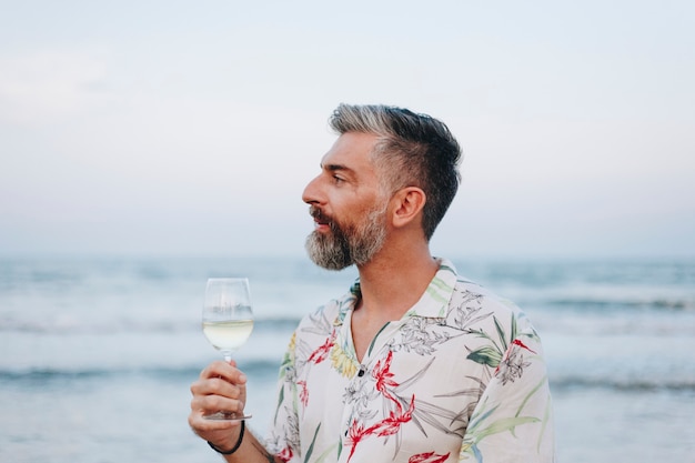 Uomo che beve un bicchiere di vino sulla spiaggia