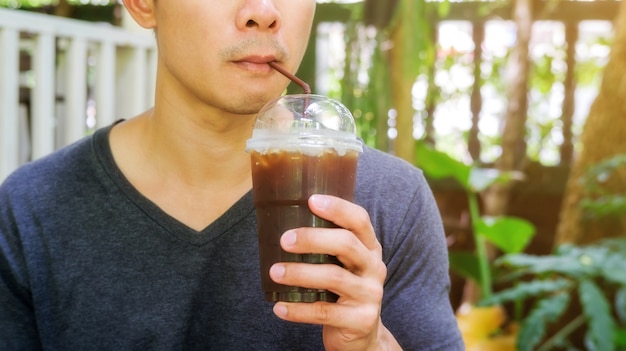 Uomo che beve un caffè americano ghiacciato