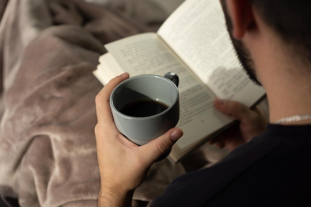 Uomo che beve un caffè durante la lettura