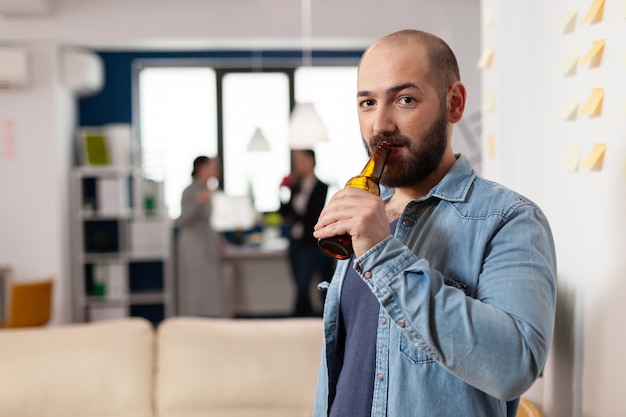 Uomo che beve una bottiglia di birra dopo una riunione di lavoro