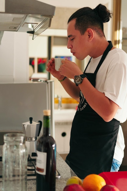 Uomo che beve una tazza di caffè in cucina a casa