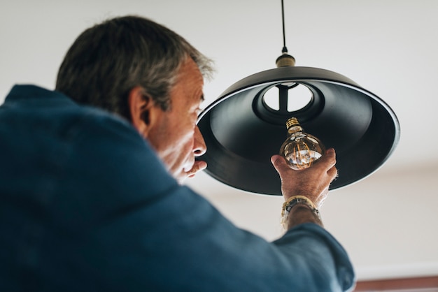 Uomo che cambia una lampadina nella sua casa