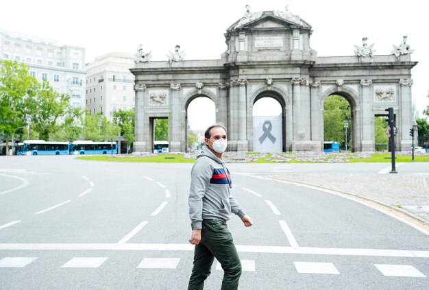 Uomo che cammina attraverso la città di Madrid con la maschera