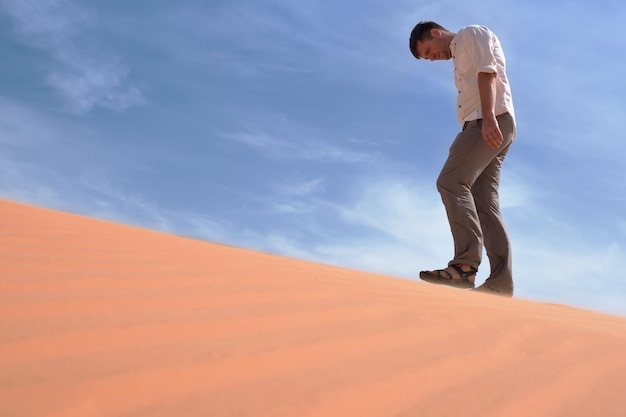 Uomo che cammina da solo nel deserto soleggiato È perso e senza fiato Senza acqua ed energia