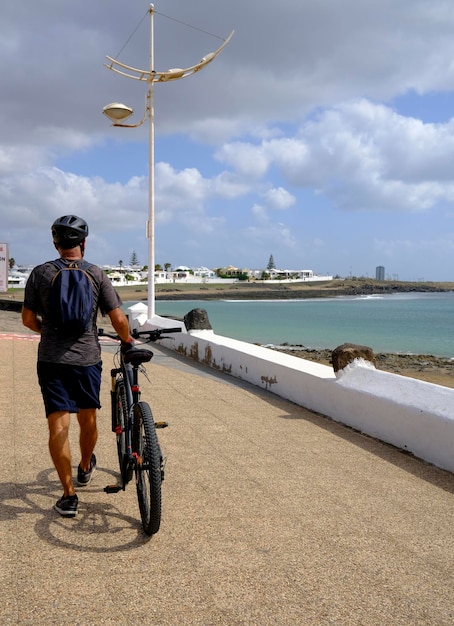 Uomo che cammina lungo il lungomare in bicicletta