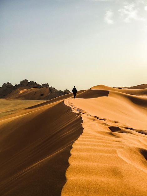 Uomo che cammina nel deserto contro un cielo limpido