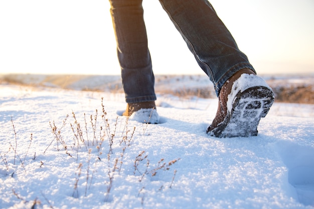 Uomo che cammina nella neve al tramonto