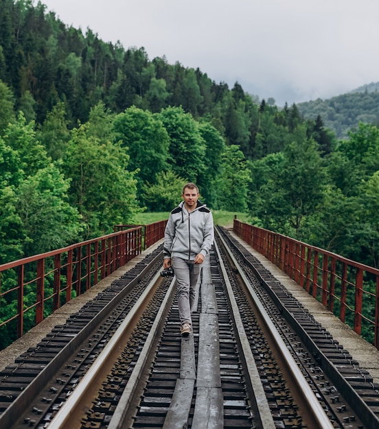 Uomo che cammina su un ponte ferroviario nel bosco