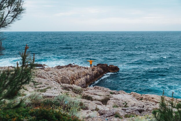 Uomo che cammina sulla roccia per prendere d'assalto lo spazio della copia del mare