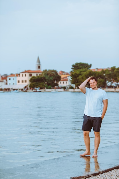 Uomo che cammina sulla spiaggia del mare nella città di fazana sera d'estate sullo sfondo in croazia