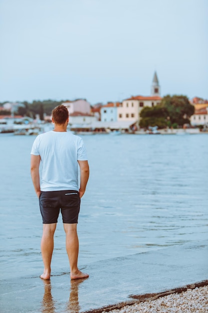 Uomo che cammina sulla spiaggia del mare nella città di fazana sera d'estate sullo sfondo in croazia