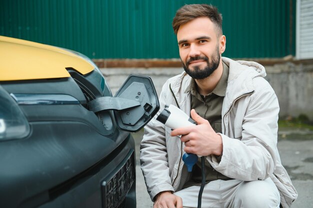 Uomo che carica auto elettrica dal lavoro