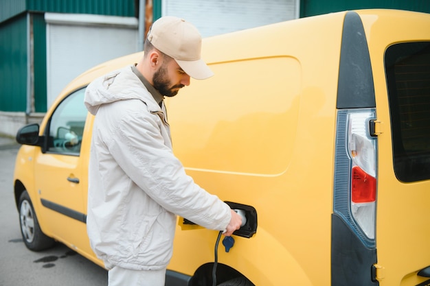 Uomo che carica auto elettrica dal lavoro