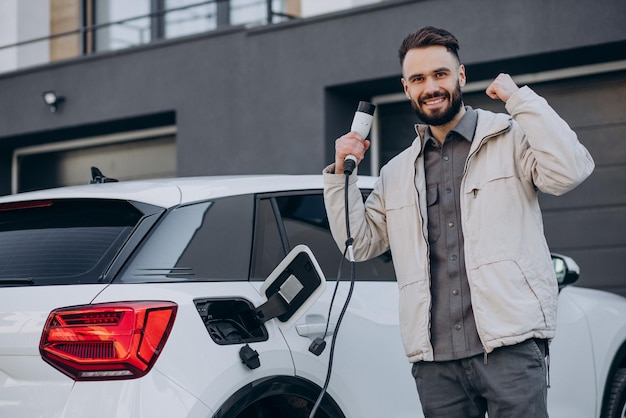 Uomo che carica un'auto elettrica vicino alla casa