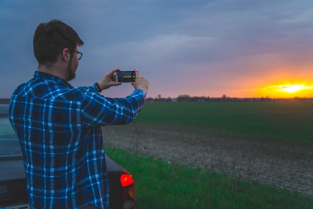 Uomo che cattura la foto dell'alba sull'autostrada