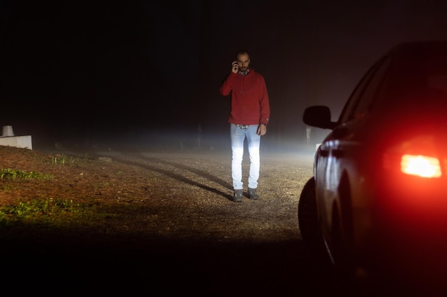 Uomo che chiama la compagnia di assicurazioni fuori dalla sua macchina in panne