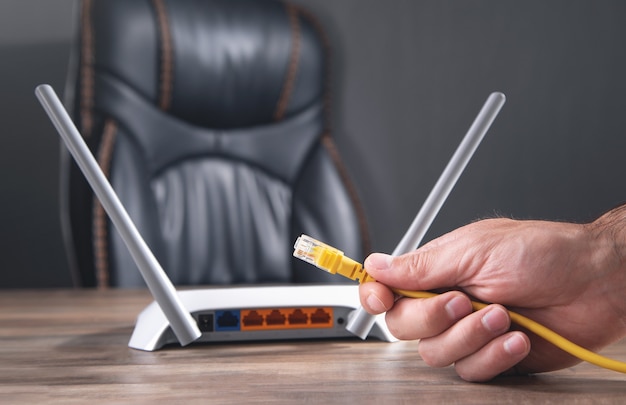 Uomo che collega il cavo internet al router wifi.