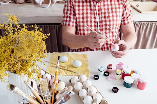 Uomo che colora le uova di pasqua nella cucina di casa