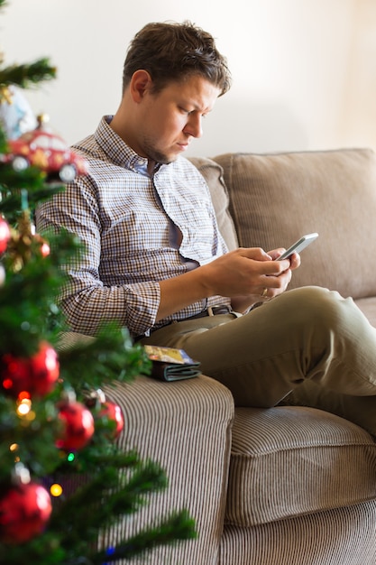 Uomo che compra i regali di capodanno di Natale online utilizzando il laptop del telefono