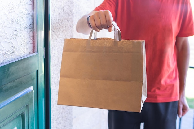 Uomo che consegna una borsa alla porta d'ingresso Acquisti online Consegna a domicilio