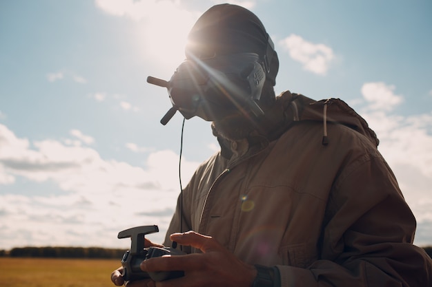 Uomo che controlla il drone quadricottero fpv con il telecomando dell'antenna per occhiali