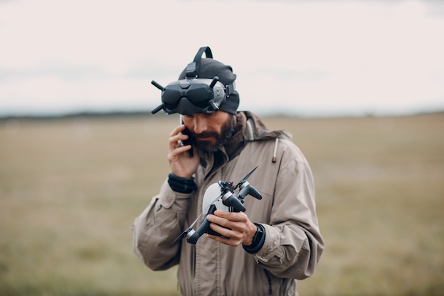 Uomo che controlla il drone quadricottero fpv per la fotografia aerea e la videografia con il telecomando dell'antenna degli occhiali.