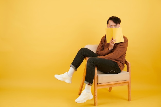 Uomo che copre la faccia con il libro aperto