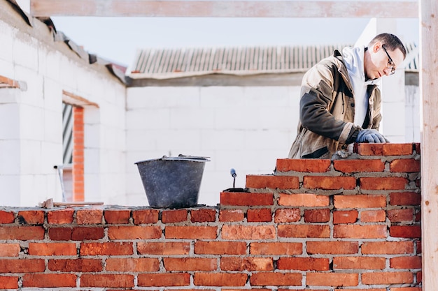 uomo che costruisce un muro di mattoni muratore