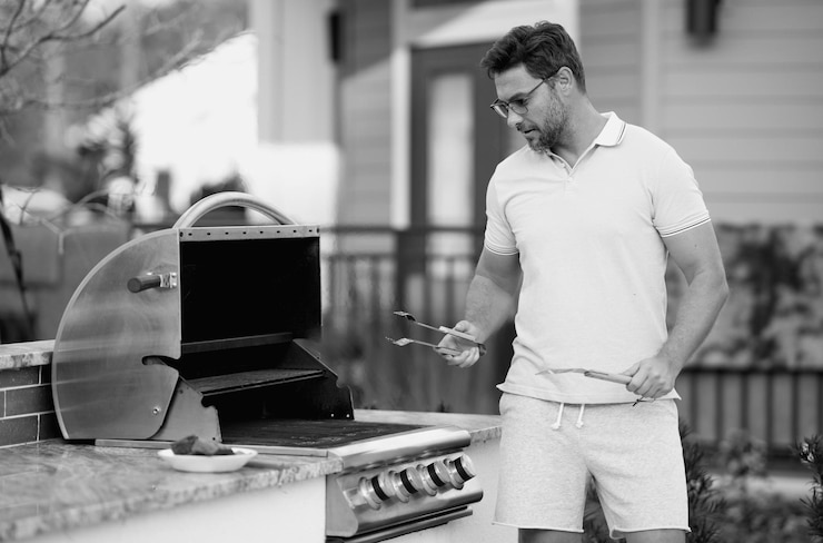 Foto uomo che cucina carne al barbecue nel cortile posteriore della casa uomo bello che prepara barbecue barbecue chef maestro cuoco che prepara deliziosi barbecue alla griglia cibo bbq carne griglia e barbecue