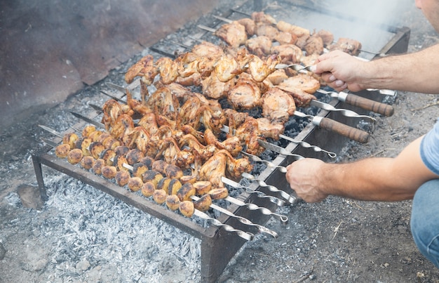 Uomo che cucina carne barbecue all'esterno