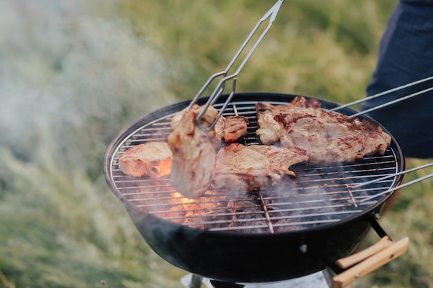 Uomo che cucina carne sulla griglia del barbecue